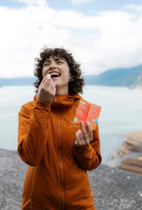 Woman enjoying Sunii Energy Gum with fresh mint flavor by a lakeside, promoting a refreshing and energizing boost