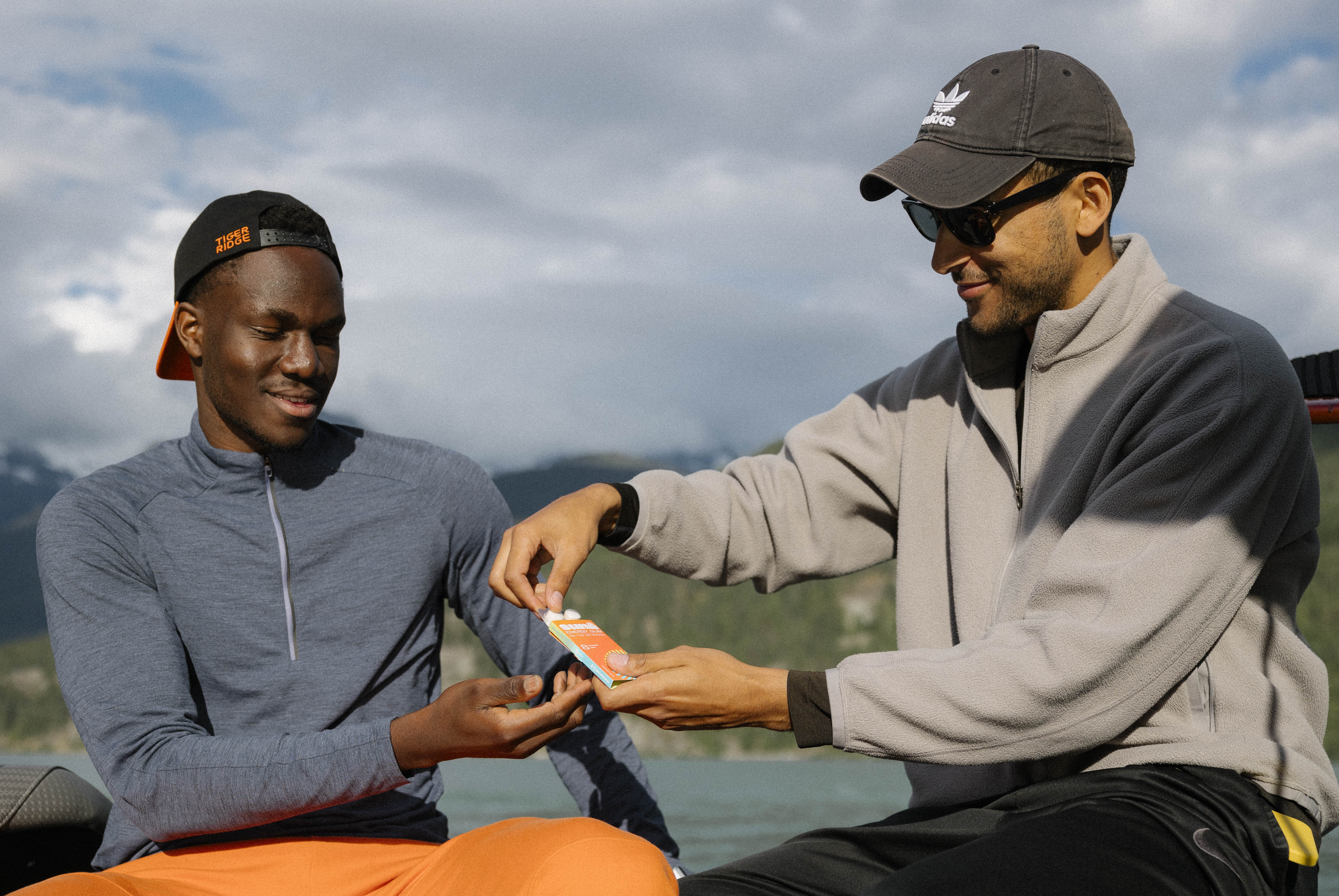 Two men sharing Sunii Energy Gum outdoors, highlighting the product’s portability and ease of use during outdoor activities