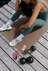 Woman sitting on a yoga mat with Sunii Energy Gum pack beside her, promoting worry-free energy that is sugar-free, gluten-free, and vegan